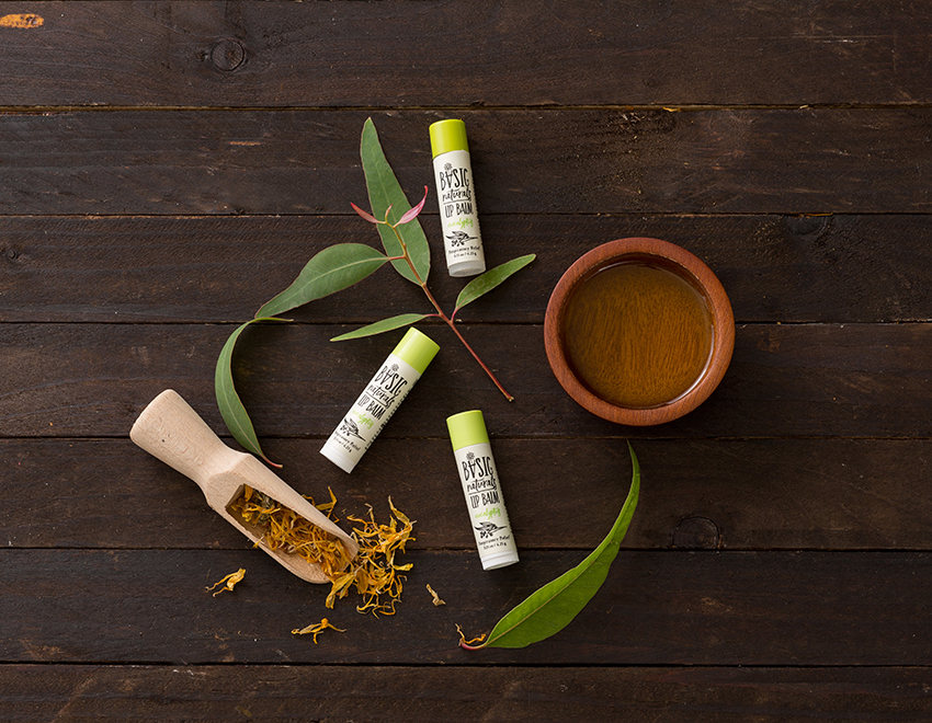 Ultimate Lip Treatment - Eucalyptus Scented Eucalyptus Lip Balm Artistic Photograph of 3 Products with Eucalyptus Leaves and Natural wood dishes and scoop on dark wood background