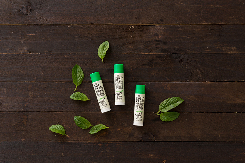 Ultimate Lip Treatment - Peppermint Scented Lip Balm Artistic Photograph of 3 Products with Peppermint Leaves and Natural dark wood background